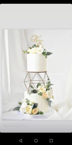 a three tiered wedding cake with white flowers and greenery on the bottom layer