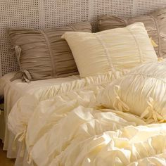 an unmade bed with white sheets and pillows