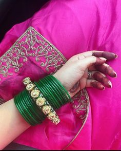 a woman wearing green bracelets and pink sari