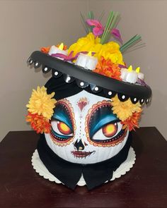 a white and black mask with flowers on it sitting on a table next to a wall