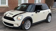 a white and black mini car parked in front of a brick building on the street