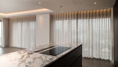 an empty kitchen with marble counter tops and white curtains in the window sill area