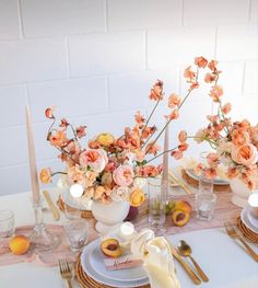 the table is set with plates, silverware and vases filled with peach colored flowers