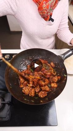 a woman cooking food in a wok on the stove