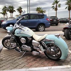 a blue motorcycle parked in a parking lot next to other motorcycles and cars on the street