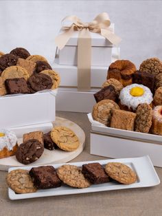 three white boxes filled with assorted cookies and pastries on top of a table