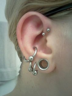 a close up of a person's ear with two piercings on it and one behind the ear