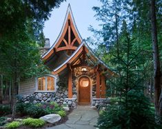 a small house in the woods surrounded by trees and rocks, with a pathway leading to it