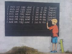 a boy writing on a chalkboard next to a green skateboard