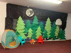 there is a tent and chairs in front of a wall decorated with paper christmas trees