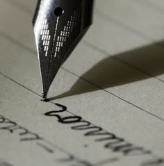 a pen writing on top of a piece of paper with the word written in cursive ink