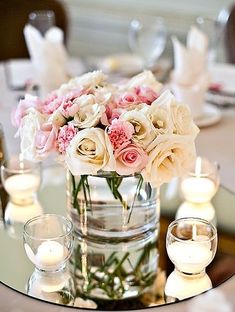 a vase filled with lots of white and pink flowers on top of a glass table