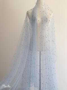 a mannequin wearing a white veil with blue beads