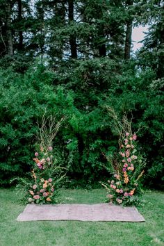 an outdoor ceremony setup with flowers and greenery on the ground in front of trees