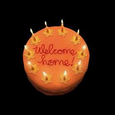 an orange cake with candles and the words welcome home written on it