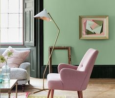 a living room with green walls and pink chairs