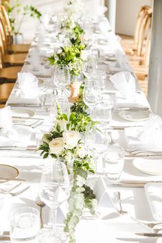 the long table is set with white and green flowers