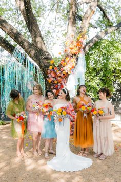 a group of women standing next to each other in front of a tree with streamers