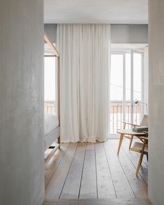 an open room with white curtains and wooden floors