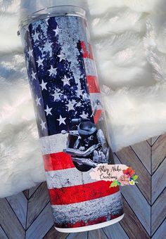 a tumbler with an american flag and skull on it is sitting on a wooden floor