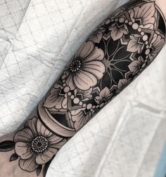 a black and white tattoo with flowers on it's arm, done by person