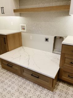 a kitchen with white marble counter tops and wooden cabinetry in the center, along with brown cabinets