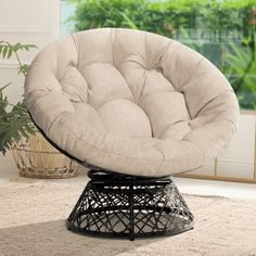 a round chair sitting on top of a rug in front of a potted plant