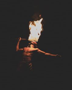 a man holding a fire stick in the dark with flames coming out of his chest