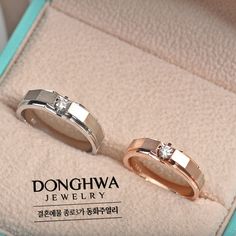 two gold wedding rings in a box with the words donghwa jewelry written on it