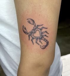 a small tattoo on the arm of a woman with a heart and crab claws in black ink