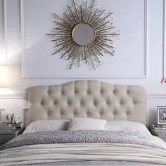 a bedroom with white walls and a sunburst on the wall above the bed