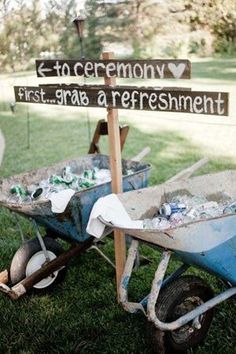 two wheelbarrows with signs on them sitting in the grass next to each other