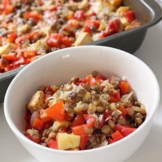 a bowl filled with food next to a baking pan full of food on a table