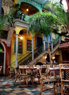 an outdoor dining area with tables, chairs and potted plants in front of the stairs