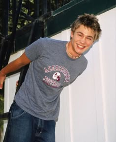 a young man is smiling and leaning against a wall