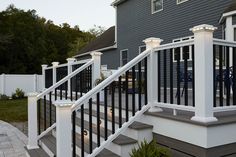 a white railing with lights on it next to a gray house in the evening time