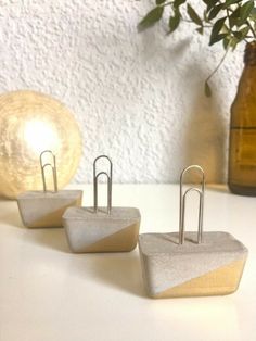 three office supplies sitting on top of a white table next to a vase with flowers