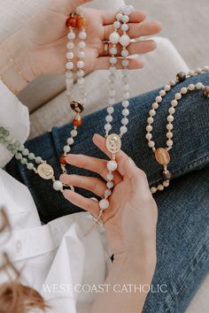 a woman is sitting on the floor with her hands holding some beads and bracelets