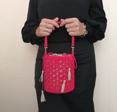 a woman holding a pink crocheted purse