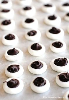 there are many chocolate covered donuts on the baking sheet with white frosting and dark brown icing