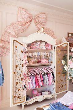 a closet filled with lots of pink and white items next to a flowery wall