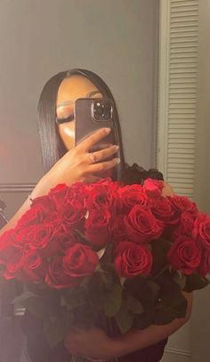 a woman taking a selfie while holding a bouquet of roses