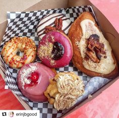 a box filled with assorted donuts on top of a checkered table cloth