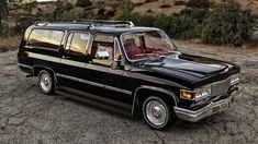 a black station wagon parked on top of a dirt field