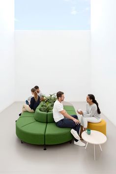 three people sitting on green couches in a white room