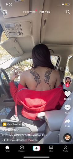 a woman sitting in the passenger seat of a car with tattoos on her back