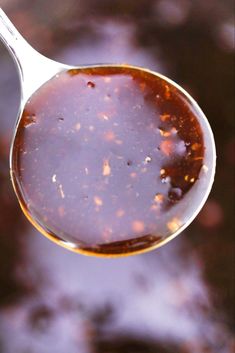 a spoon filled with brown liquid sitting on top of a table