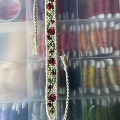 a close up of a beaded object in a box with other beads and thread