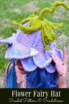 a woman with blue hair wearing a crocheted hat and holding her hands up to her face