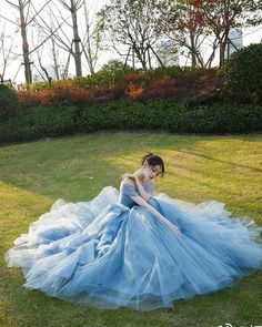 a woman in a blue dress sitting on the grass